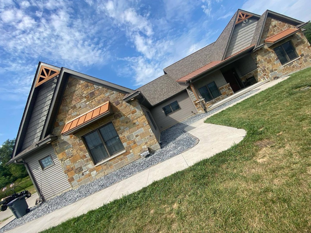 New concrete walkway and drainage border on a sloped stone-front Quad Cities home